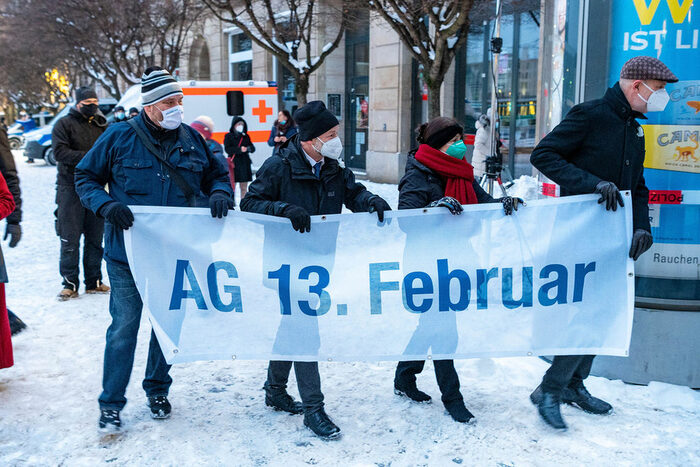 Vier Personen tragen ein Banner mit der Aufschrift "AG 13. Februar"