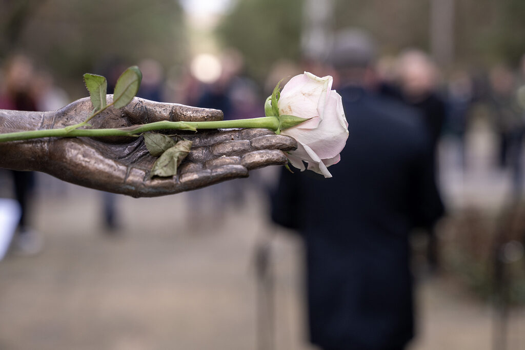 Eine weiße Rose in der Hand der Skulptur „Trauerndes Mädchen am Tränenmeer“