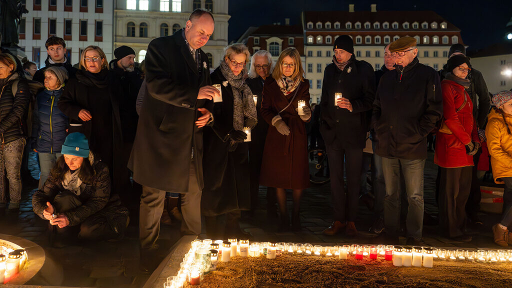 Der Oberbürgermeister und weitere Menschen stellen Kerzen zum Gedenken ab