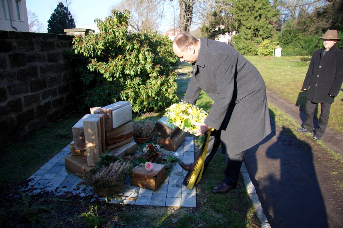 Oberbürgermeister Dirk Hilbert legt ein Blumengesteck an der Grabanlage nieder