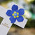 weißes Kreuz mit blauer Blume und Schriftzug Zum Gedenken