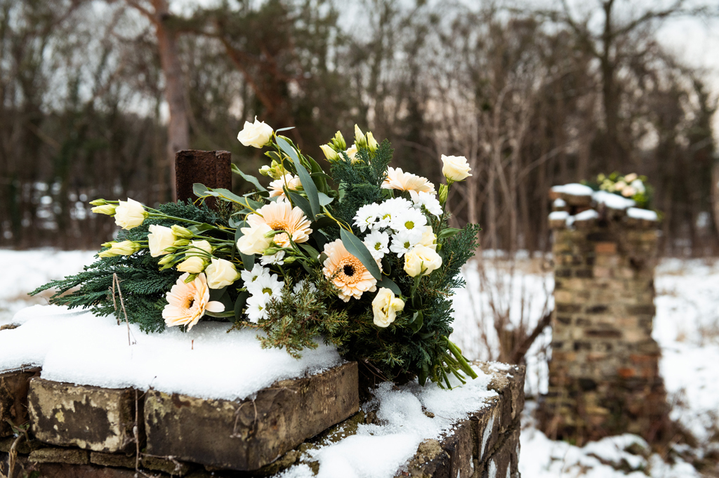 Blumenstrauß auf schneebedekctem Mauerpfosten