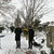 Frau mit Akordeon und zwei Männer auf verschneitem Friedhof