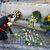 Ein Mann legt weiße Rosen nieder, dahinter liegen Blumenkränze an einer Gedenkstätte