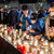 Personen stehen an einem langen Tisch mit vielen Kerzen und Teelichtern