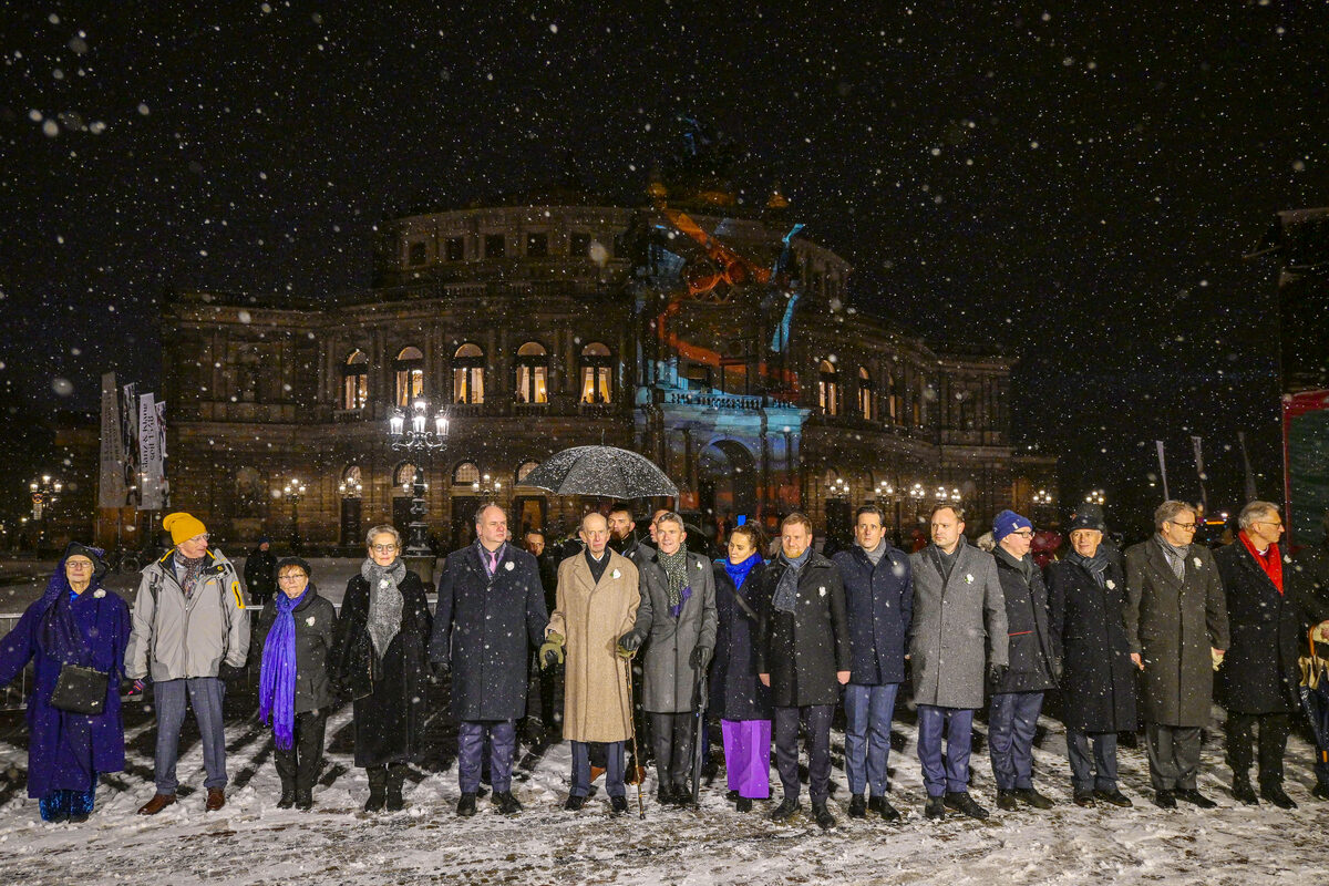 Mehrere Menschen stehen Hand in Hand vor der Semperoper