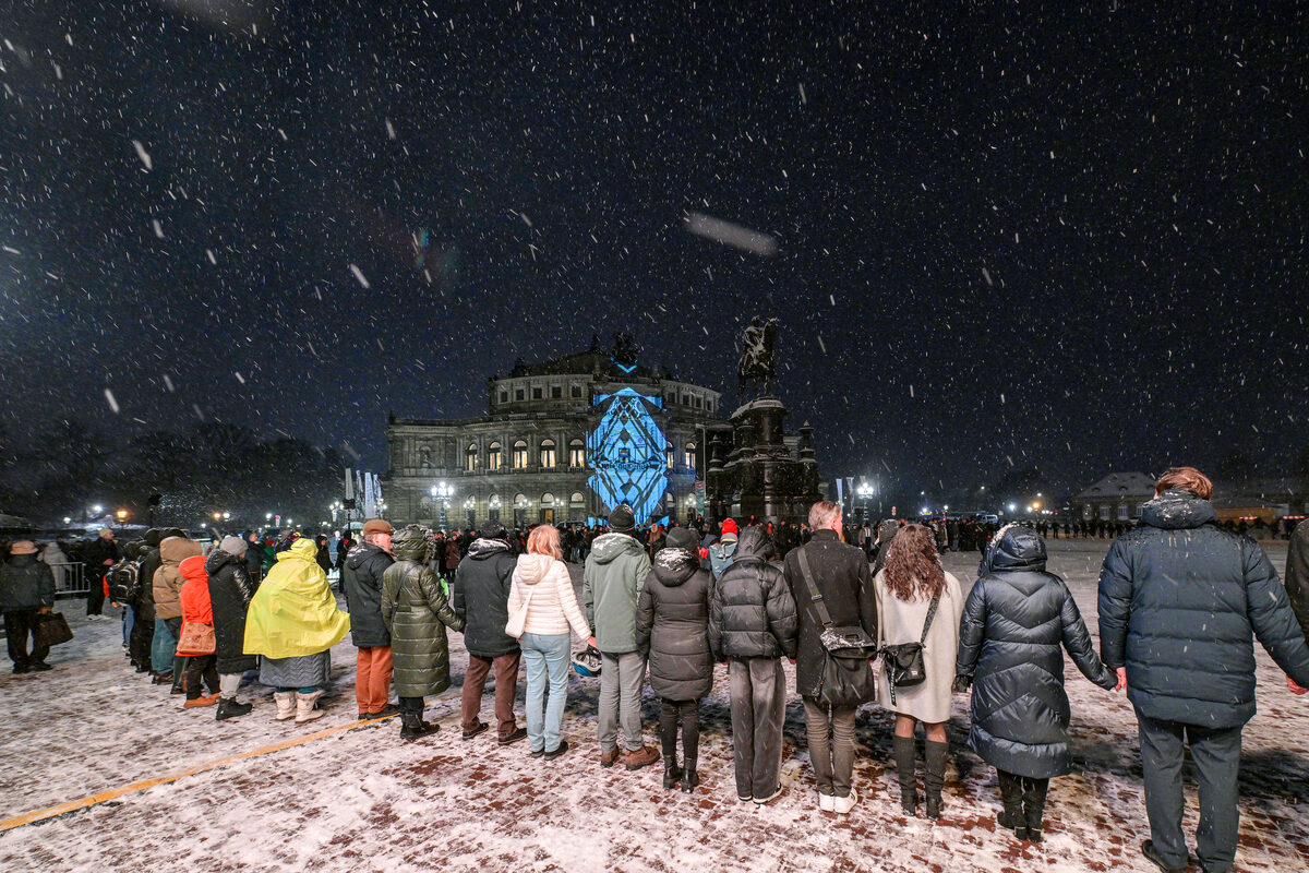 Mehrere Menschen stehen Hand in Hand auf dem Theaterplatz