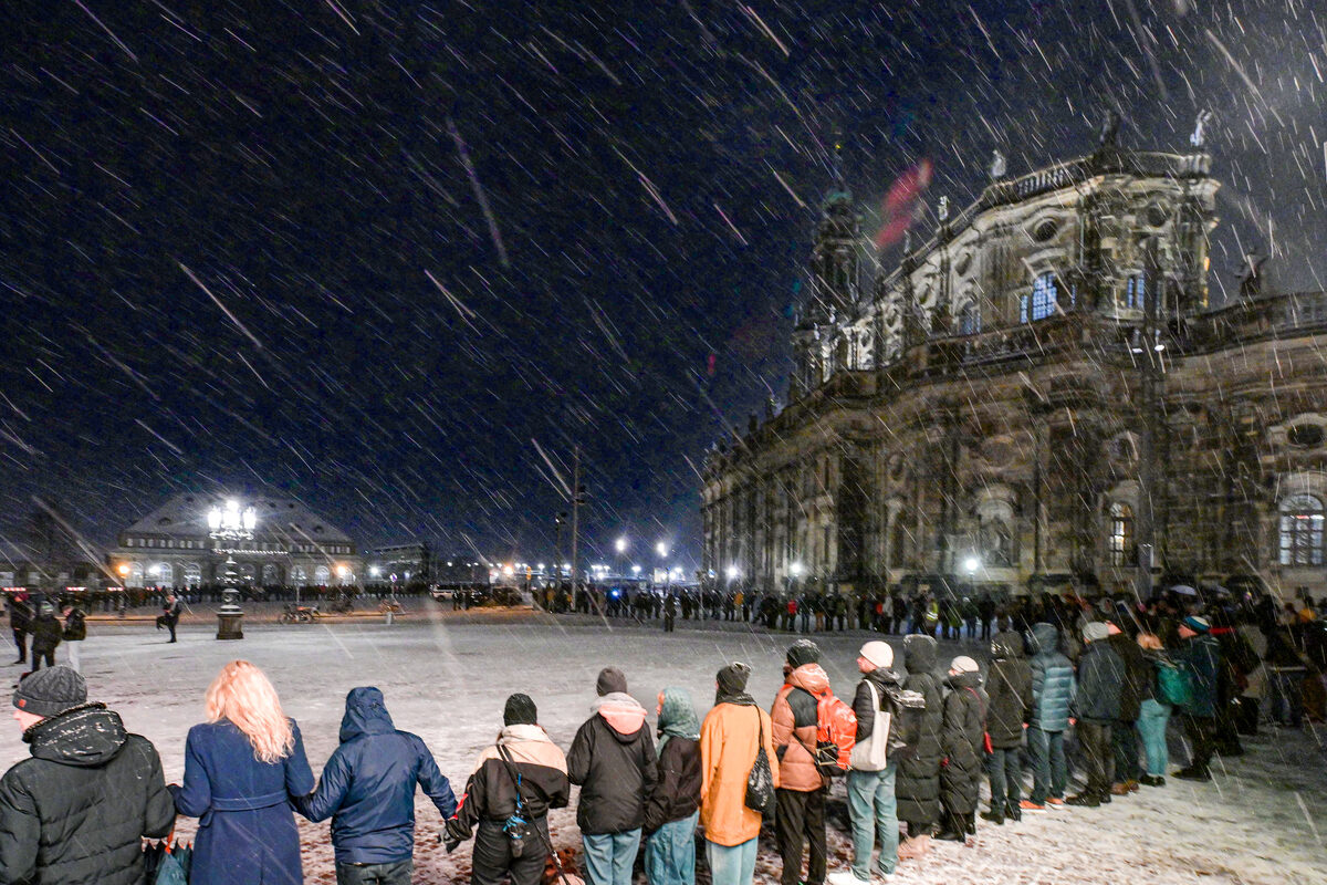 Mehrere Menschen stehen Hand in Hand auf dem Theaterplatz