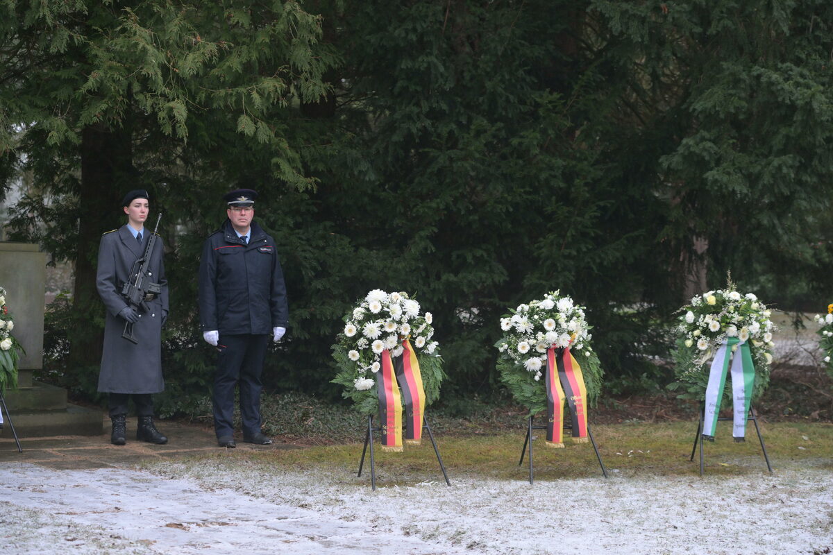 Zwei Menschen in Uniform stehen nehmen Kränzen