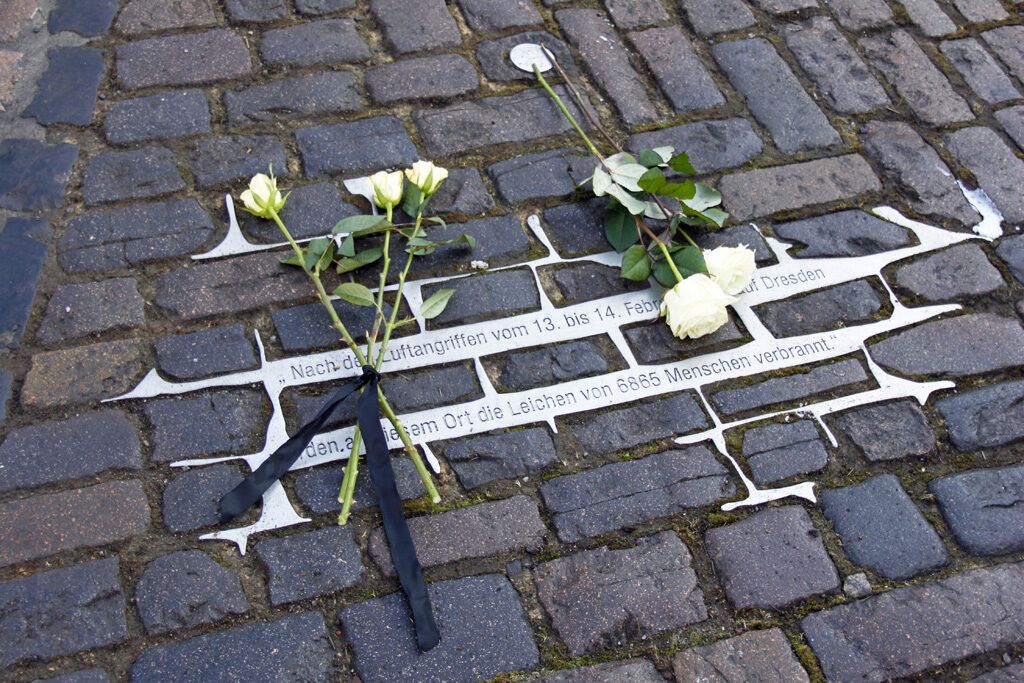 Weiße Rosen auf dem ausgegossenen Pflaster am Altmarkt