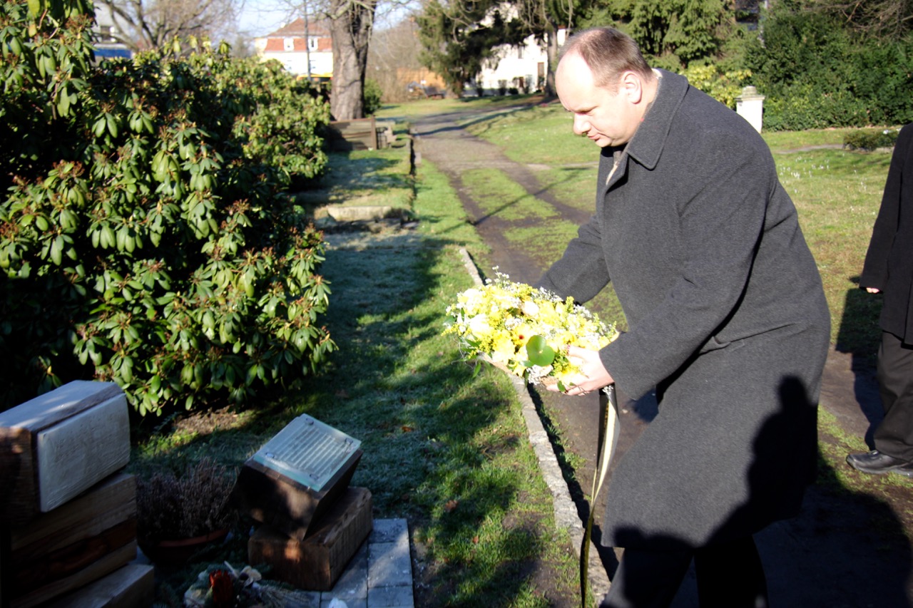 Oberbürgermeister Dirk Hilbert legt ein Blumengesteck an der Grabanlage nieder