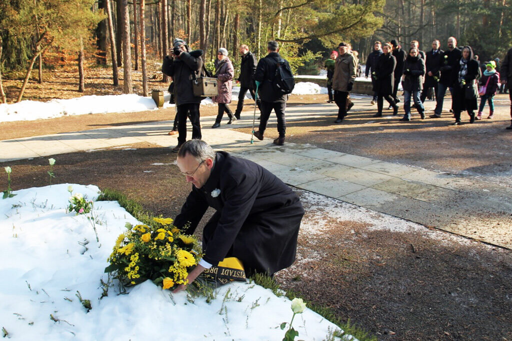 Dr. Peter Lahmes legt ein Blumengebinde auf dem Heidefriedhof nieder